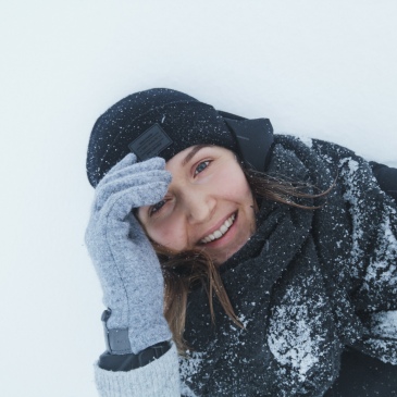 person lying in the snow and smiling to the camera